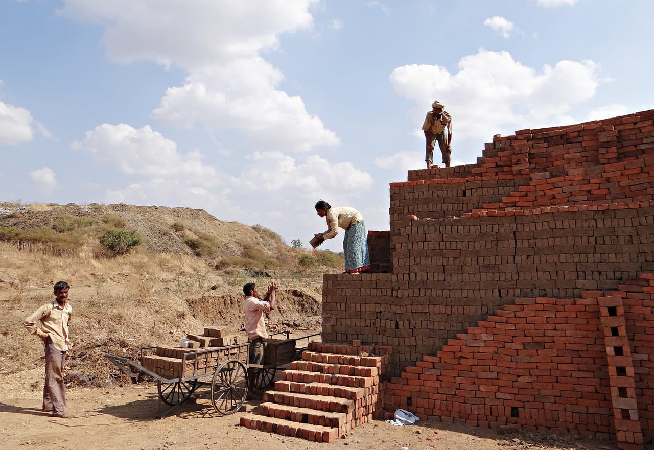 Workers stacking red clay bricks at a brick kiln in India
