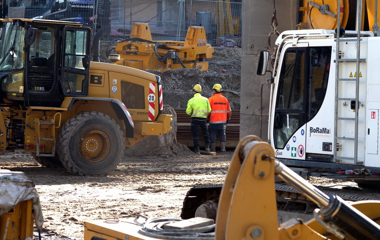 A single site supervisor in a hard hat overseeing an active residential construction site