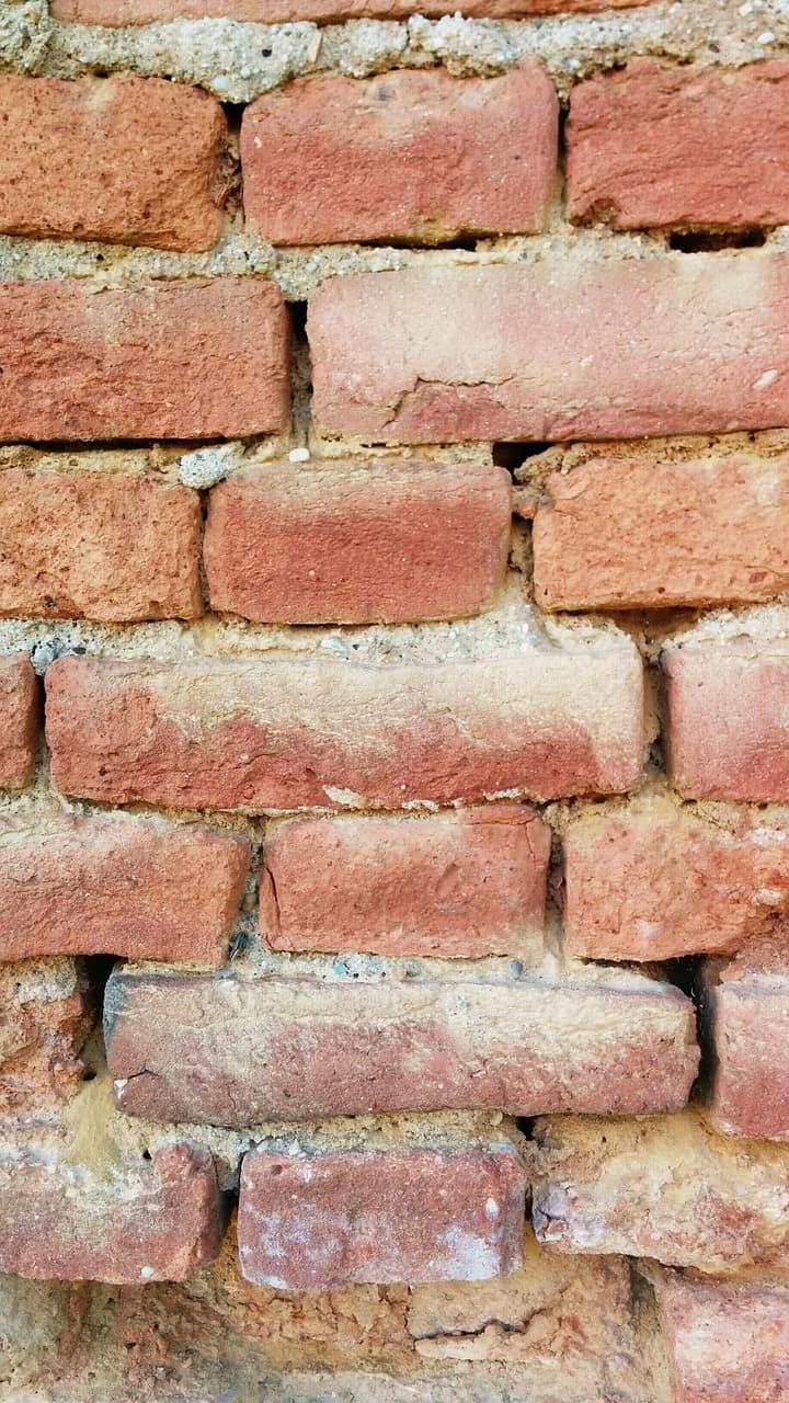 Close-up of a brick and mortar wall under construction showing masonry bonding pattern